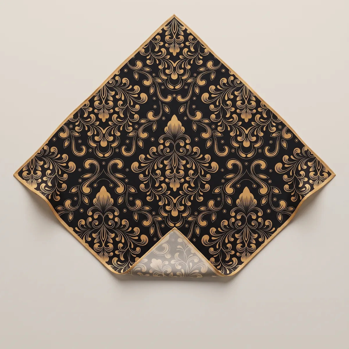 Black and gold baroque silk bandana laid out on its point, gold scrollwork on black inside a narrow gold border