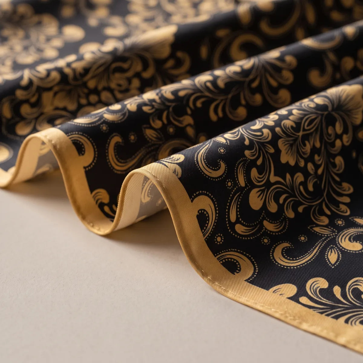 Folds of black silk printed with gold leafy scrolls and dotted swirls, edged in gold