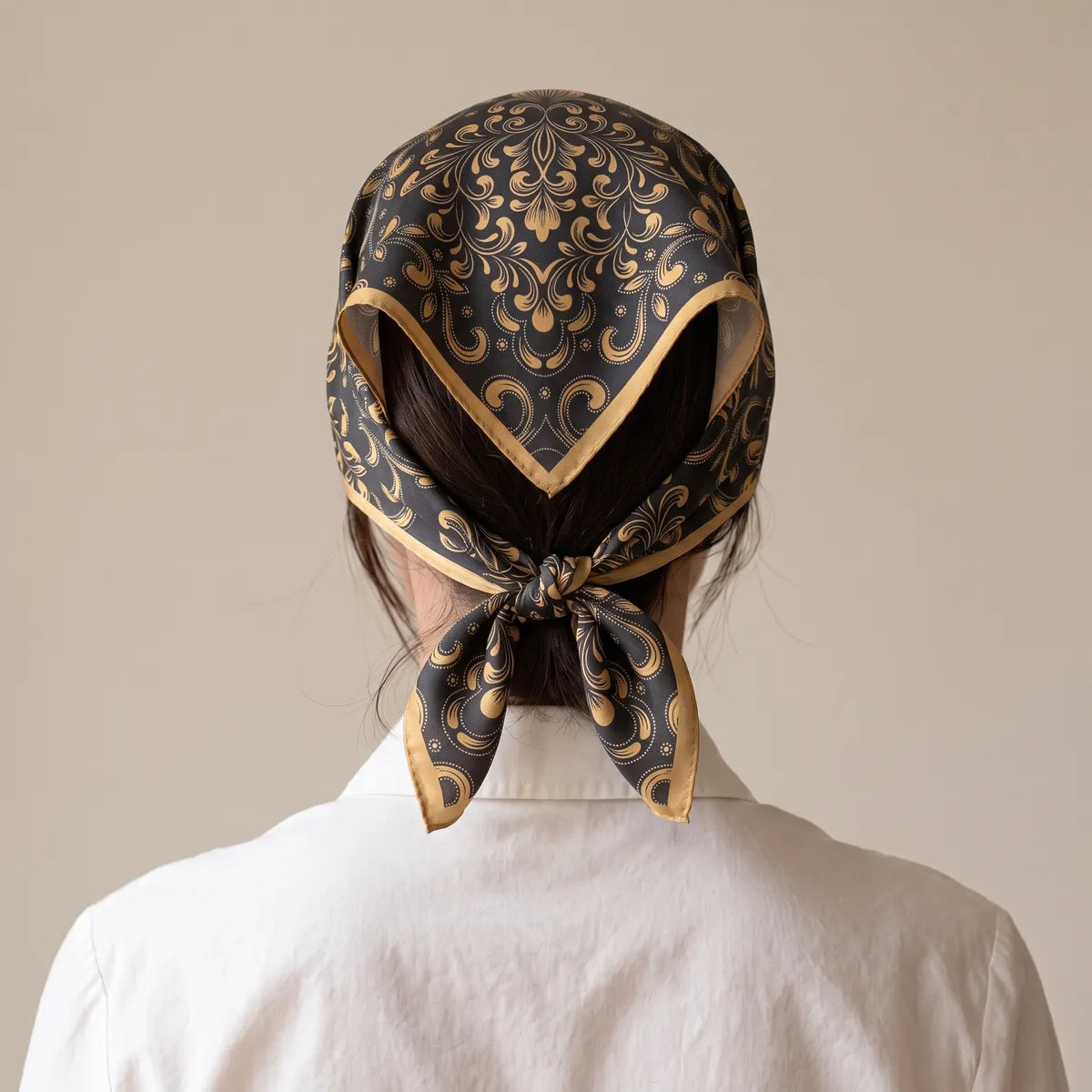 Back view of the gold scrollwork bandana over the hair, its gold border meeting at the nape knot