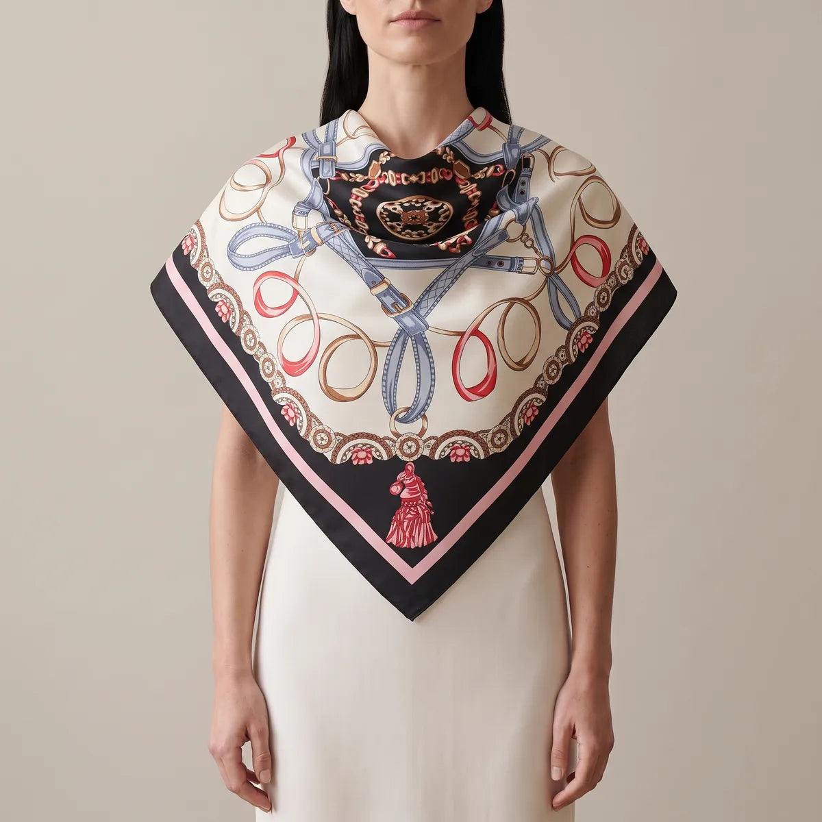 Woman wearing a black chain print silk shawl over the shoulders like a short cape, red tassel at the front