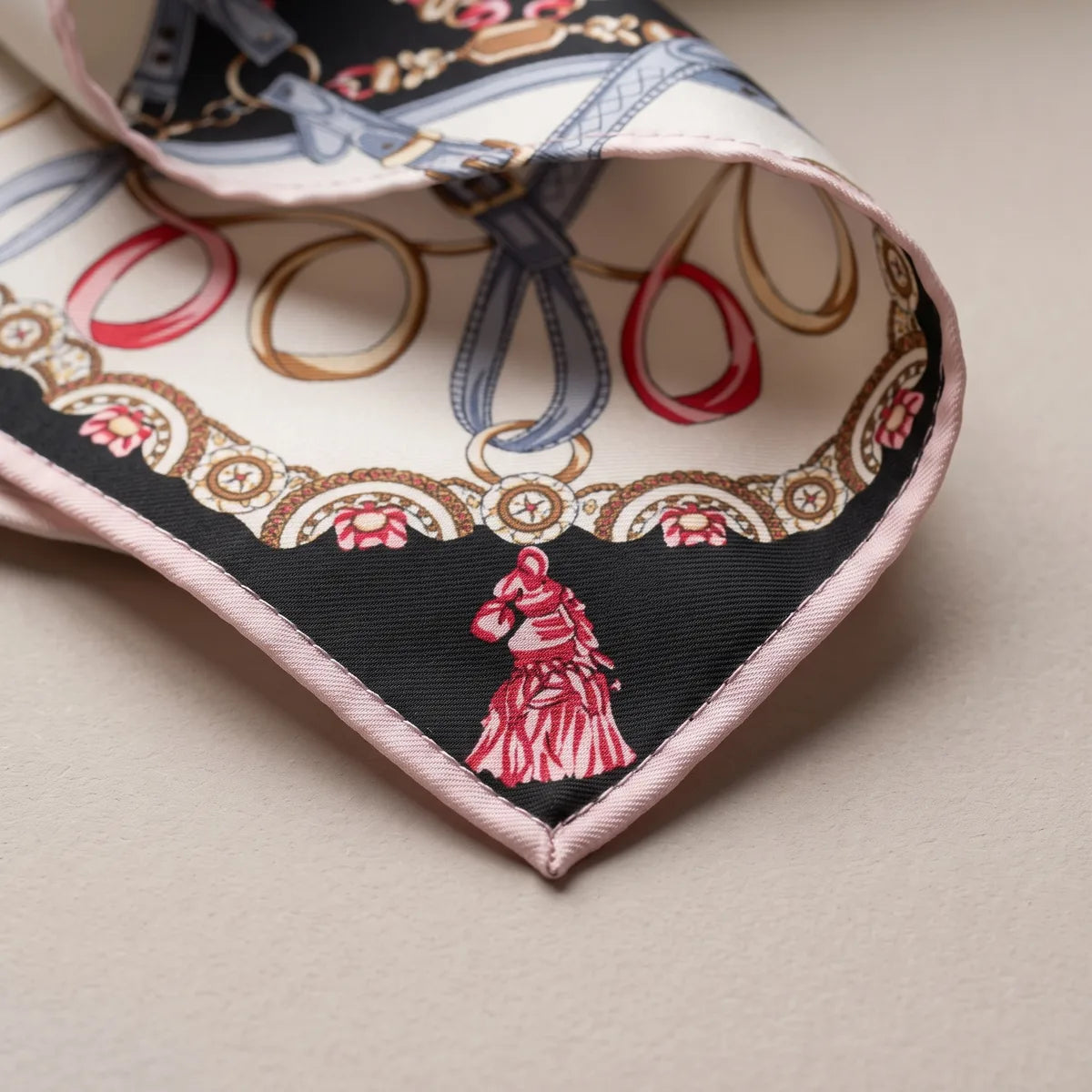 Corner of the black shawl: a red horse-head tassel on black, a beaded garland and the blush pink edge