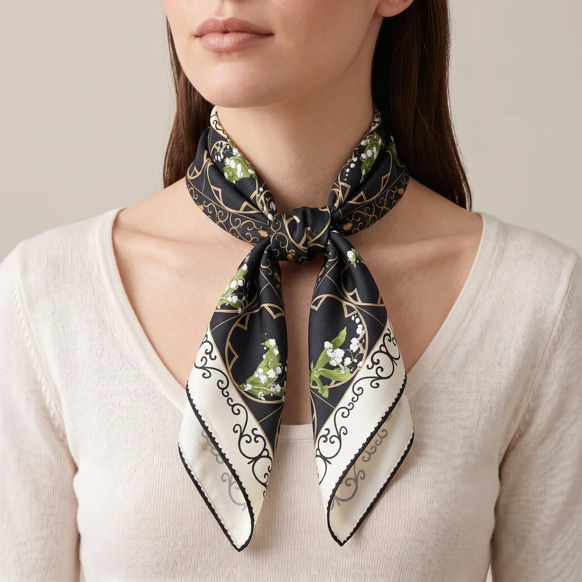 Black lily print square worn in a throat knot, the cream scroll border on both tails over a knit