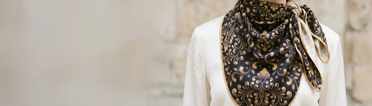 Black and gold baroque print silk bandana knotted at the neck over a cream blouse