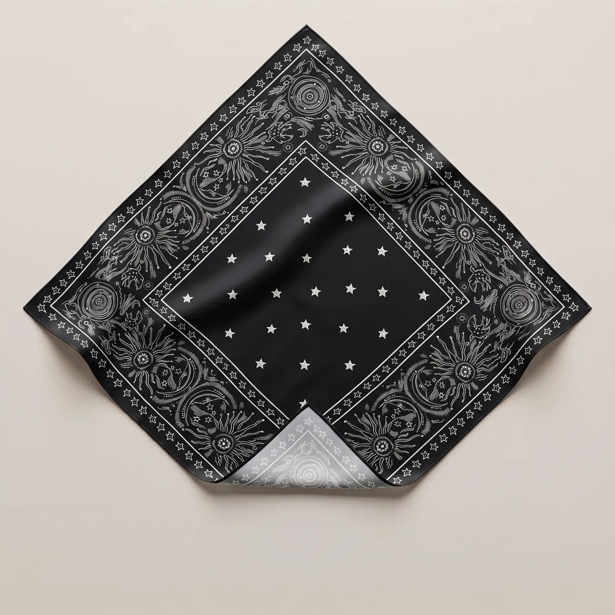 Black star print silk bandana laid flat, white stars in the center and a sun and orbit border, corner folded