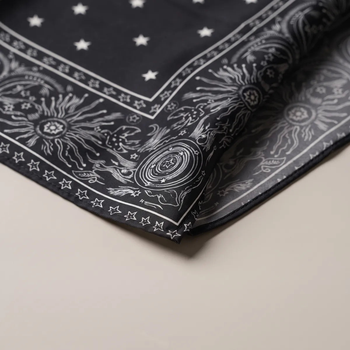 Corner of the black star bandana with a blazing sun, concentric rings and the star chain hem