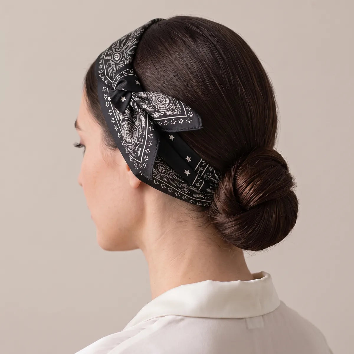Black star bandana tied as a headband over a low bun, sun motifs along the band