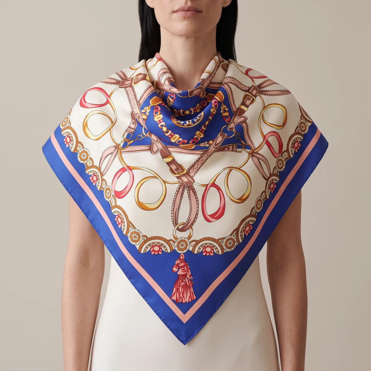 Woman in a cream dress wearing a blue chain print silk shawl across the shoulders, its tasseled point hanging down the front