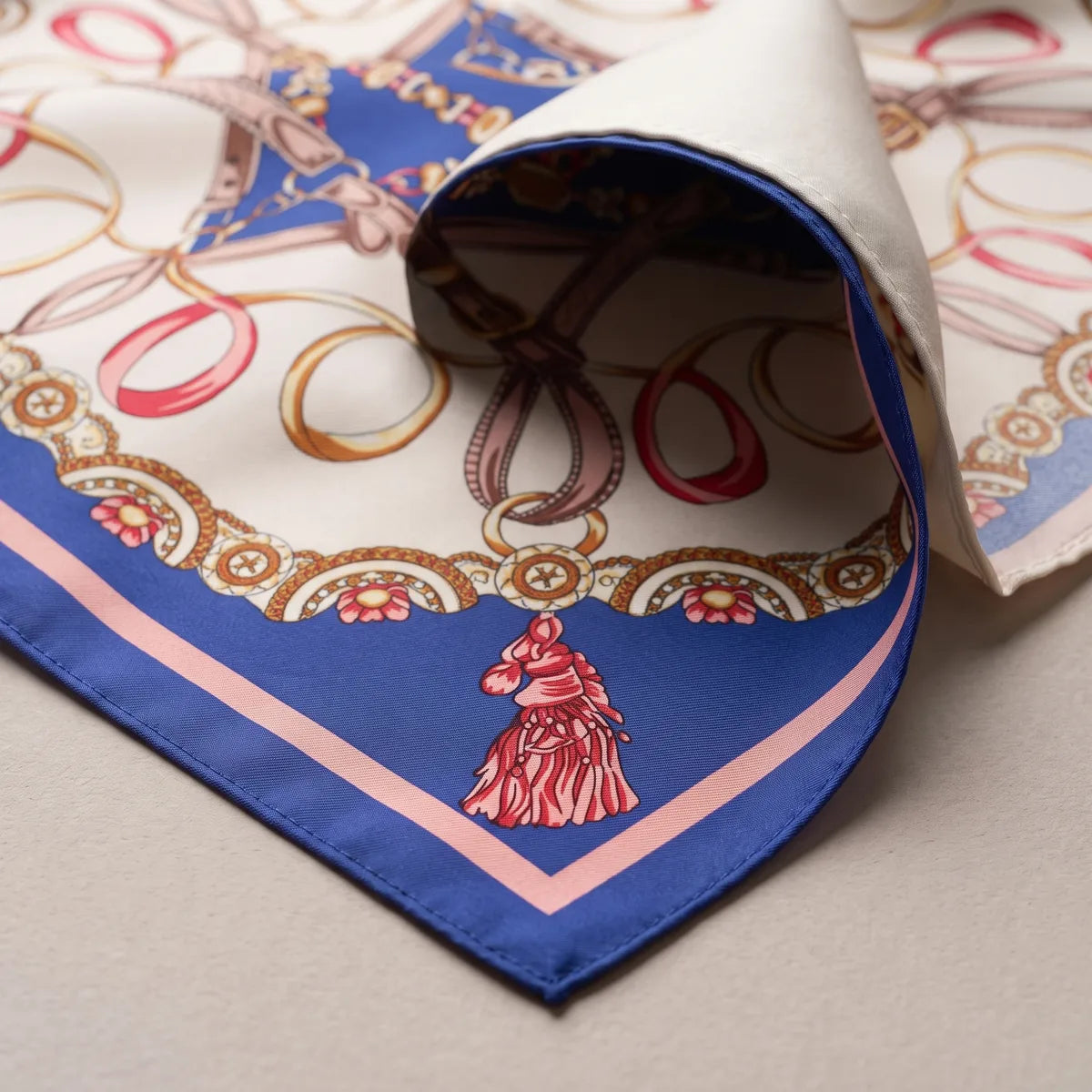Royal blue corner of the shawl with a red horse-head tassel and a pink stripe, the paler reverse curling up