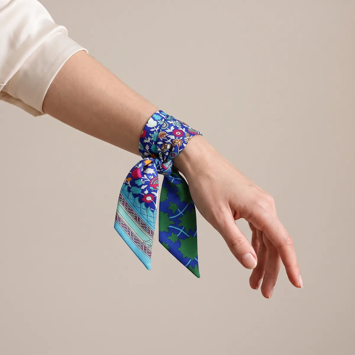 Blue and green skinny silk scarf wrapped around the wrist and knotted like a bracelet