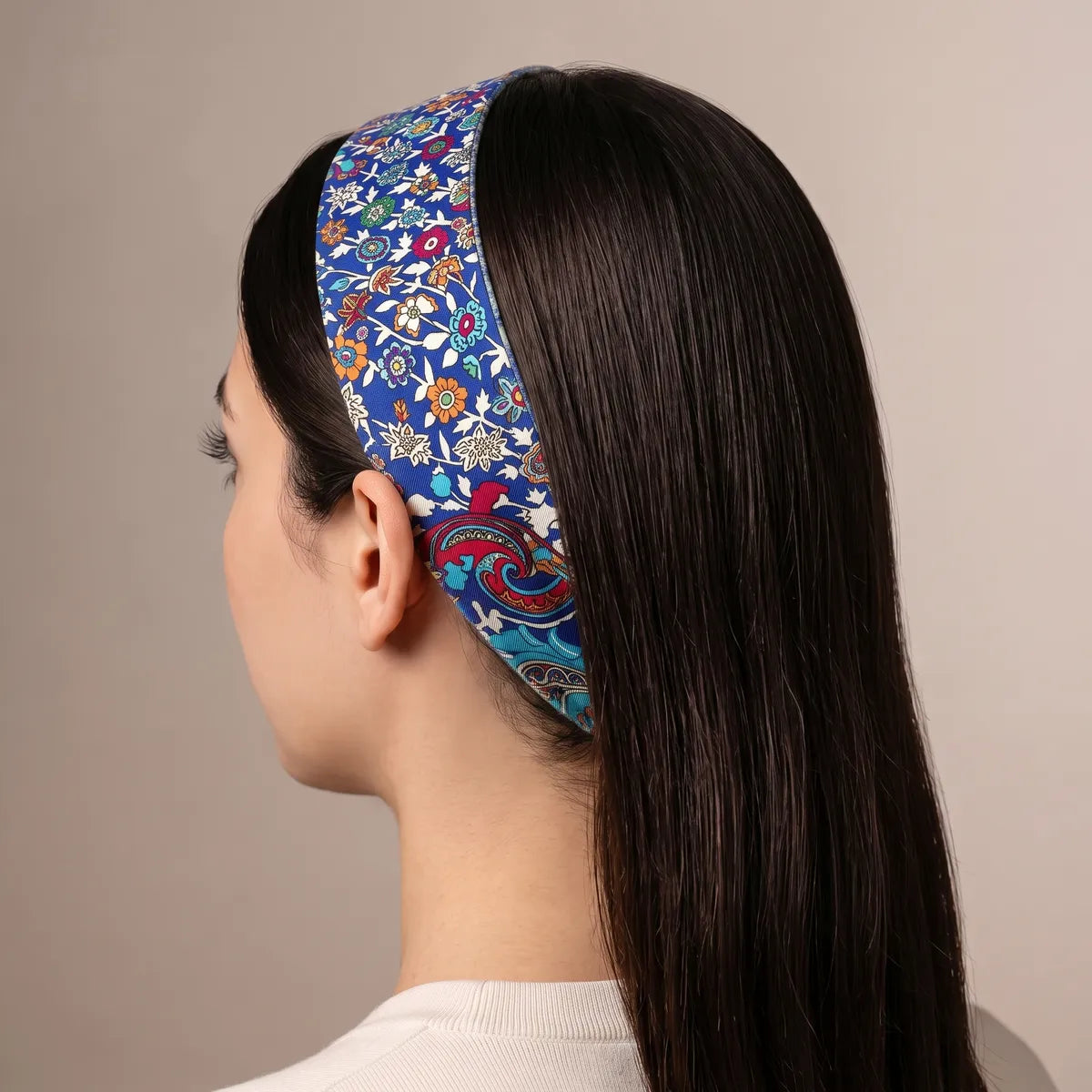 Blue floral skinny scarf worn as a headband over long dark hair, seen from behind with the floral side on top