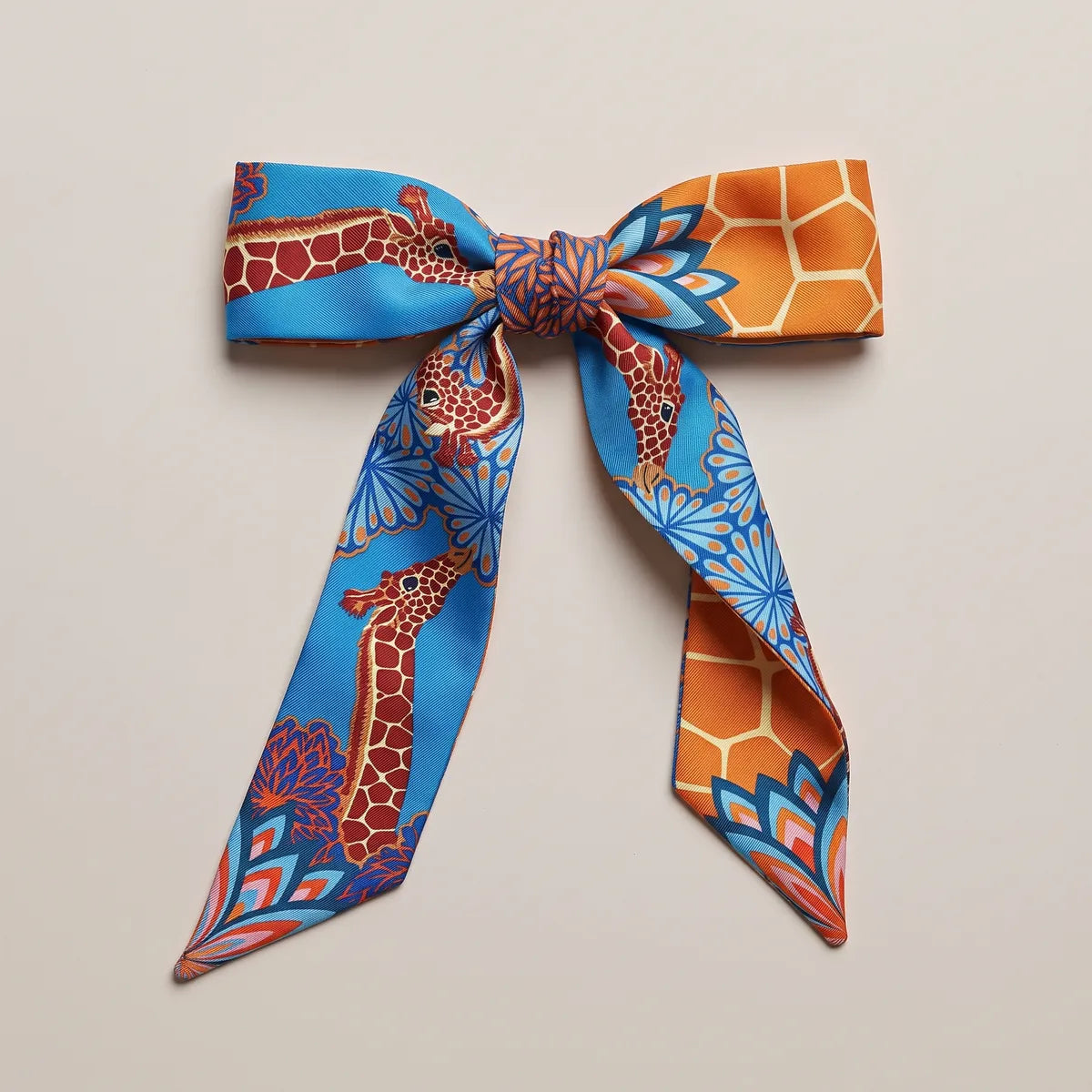 Azure skinny silk scarf tied in a flat bow, a giraffe on one loop and orange honeycomb on the other