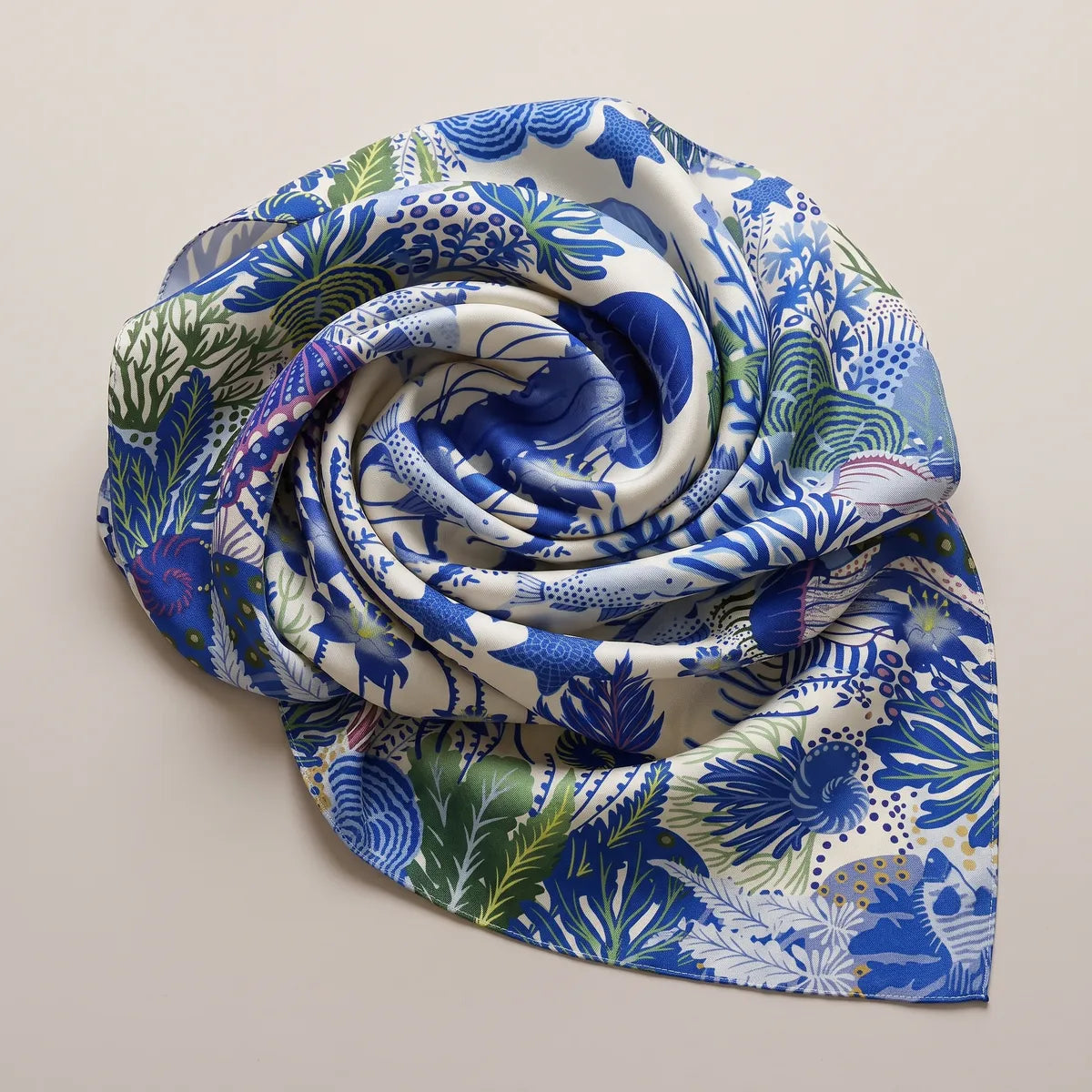 Blue and cream reef print silk shawl twisted into a rose shape, coral fronds spiraling around the center
