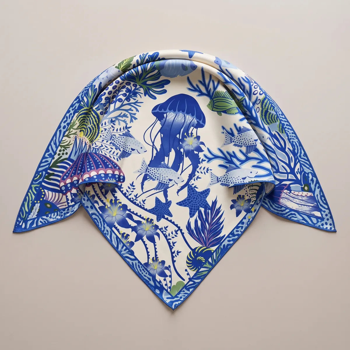 Cream and cobalt sea life shawl folded in a triangle, a big blue jellyfish at the top and a patterned blue edge