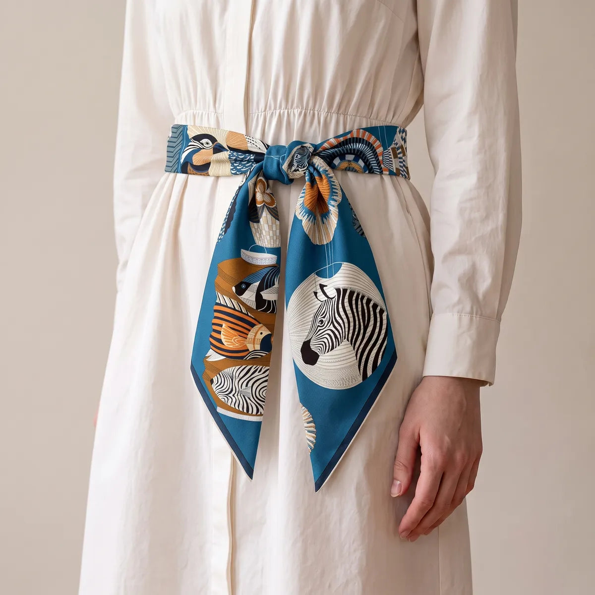 Blue lantern print silk square tied as a belt on a white shirtdress, a zebra lantern on one tail