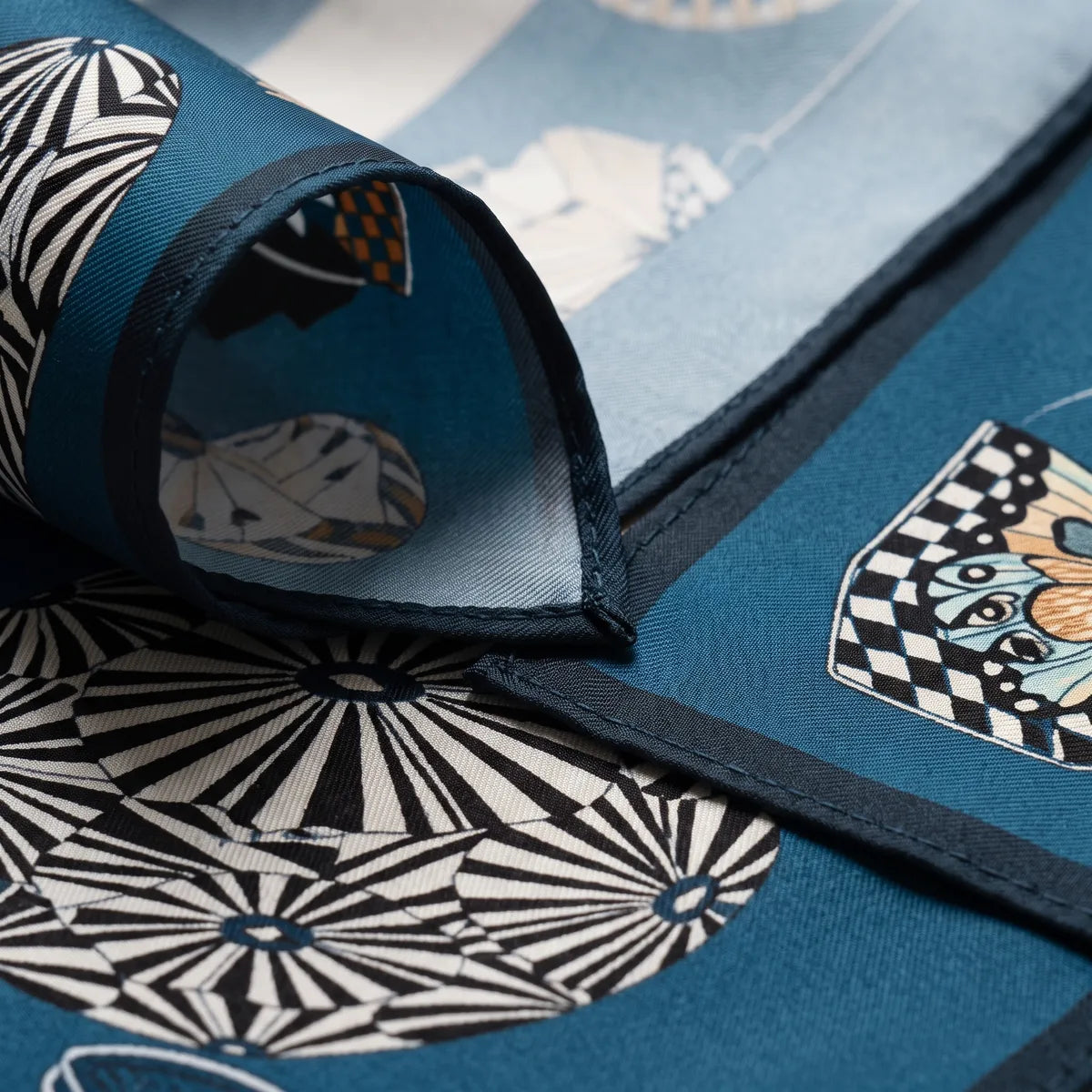 Close-up of the blue lantern scarf's corner turned back, navy edge and a pale blue reverse