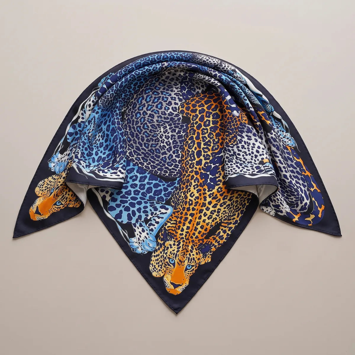 Blue leopard silk shawl folded into a triangle, the orange leopard's head at the lower point and a navy edge