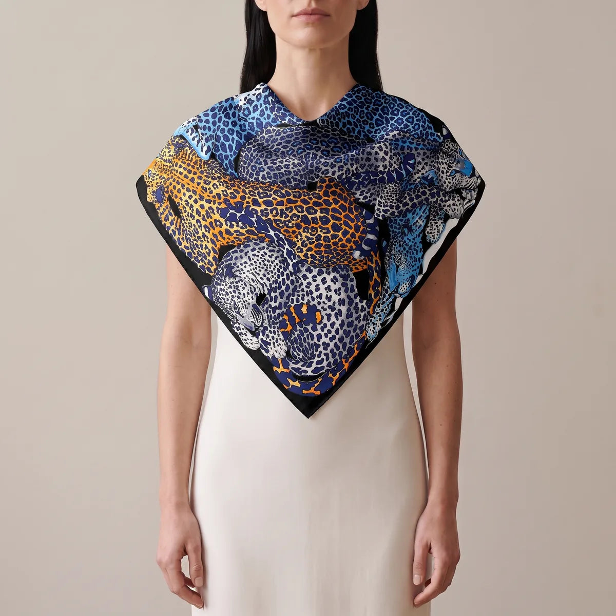 Woman wearing the blue leopard print silk shawl over her shoulders like a short cape, an orange leopard at the front