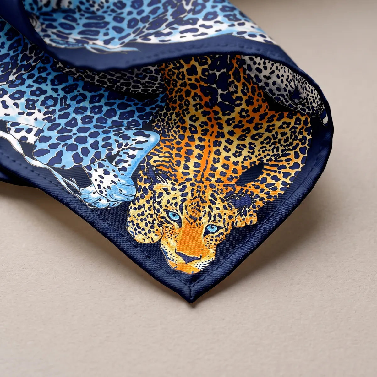 Corner of the blue shawl: an orange leopard's face with pale blue eyes above the navy hem
