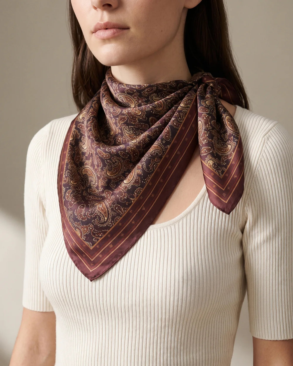 Burgundy paisley silk bandana folded in a triangle and knotted at the side of the neck