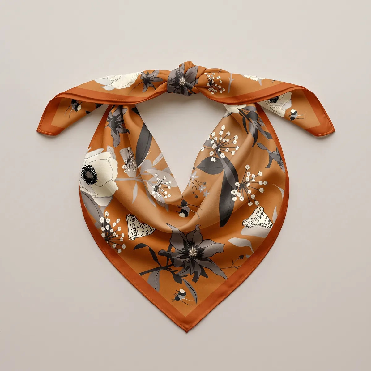 Rust-orange silk bandana tied into a loop, a white anemone and a spotted moth on the front