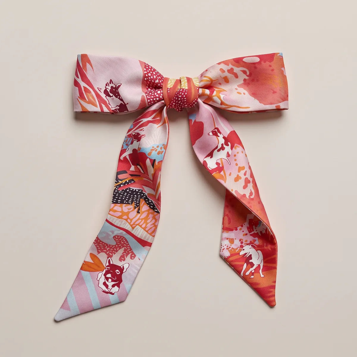 Coral skinny silk scarf tied in a flat bow, dotted pink knot and a terrier on the left loop