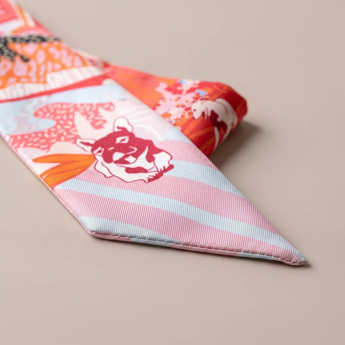 Tip of the coral skinny scarf with a crimson terrier face on pink and pale blue stripes