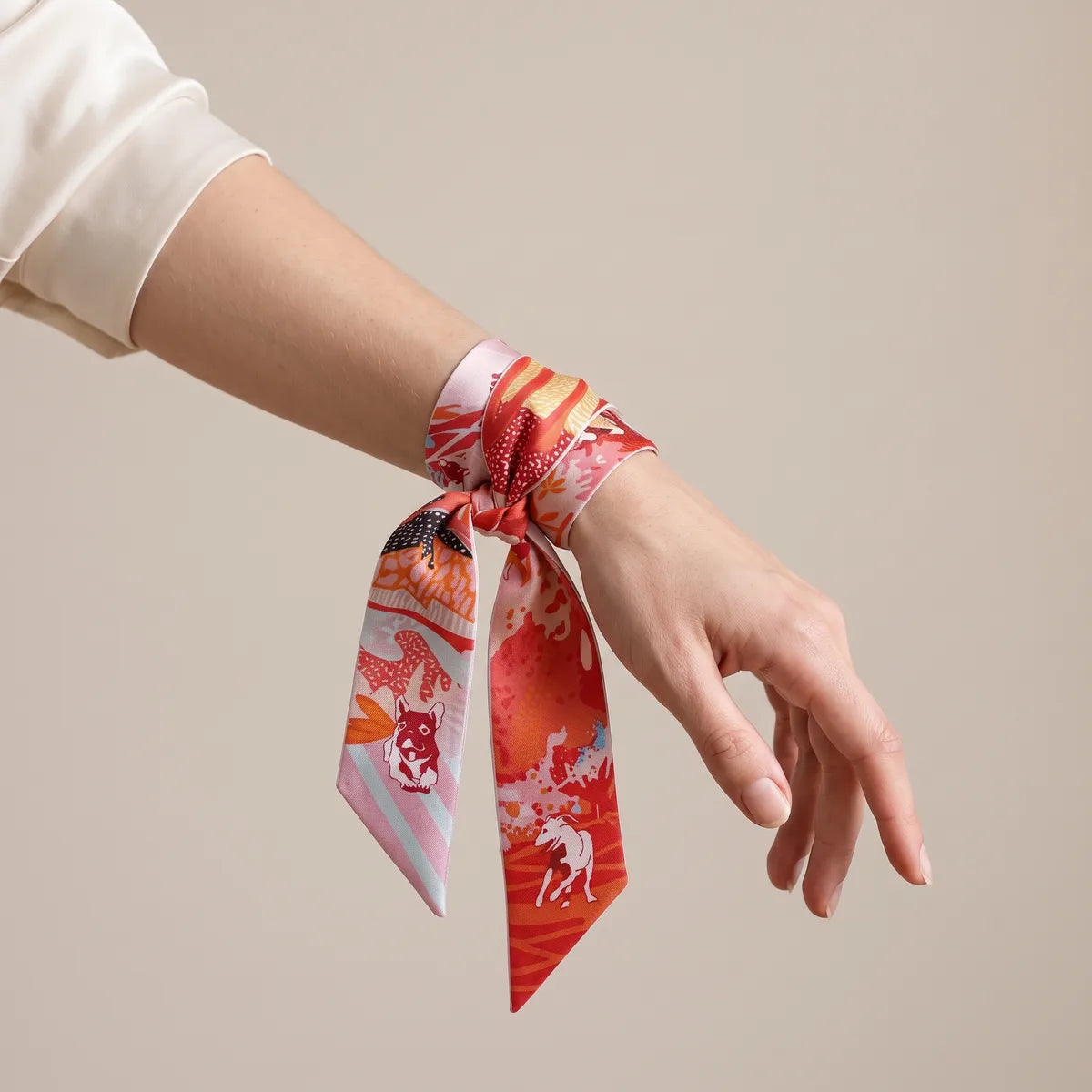 Coral terrier skinny scarf knotted around the wrist, red end hanging