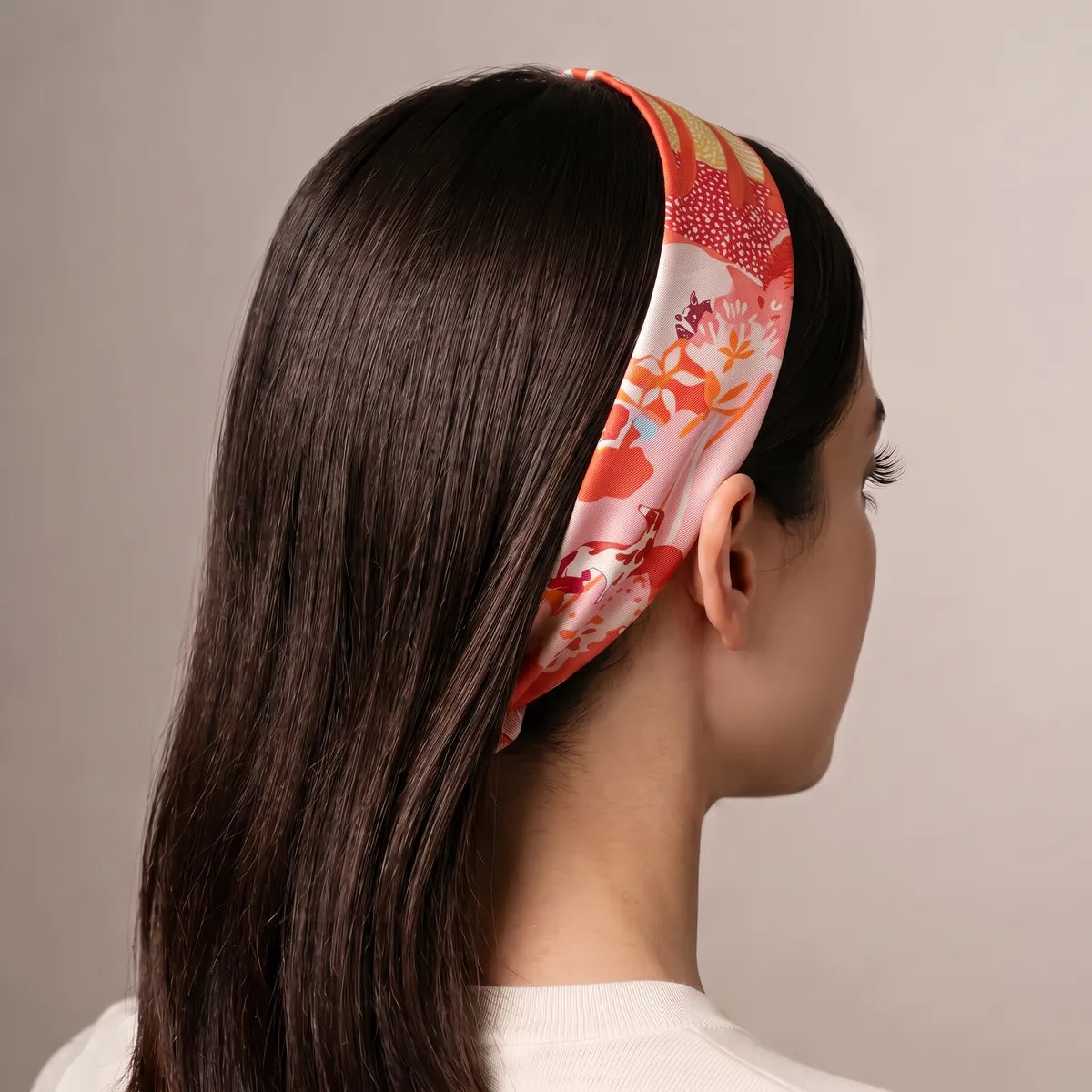 Coral and pink dog print skinny scarf worn as a headband on long dark hair