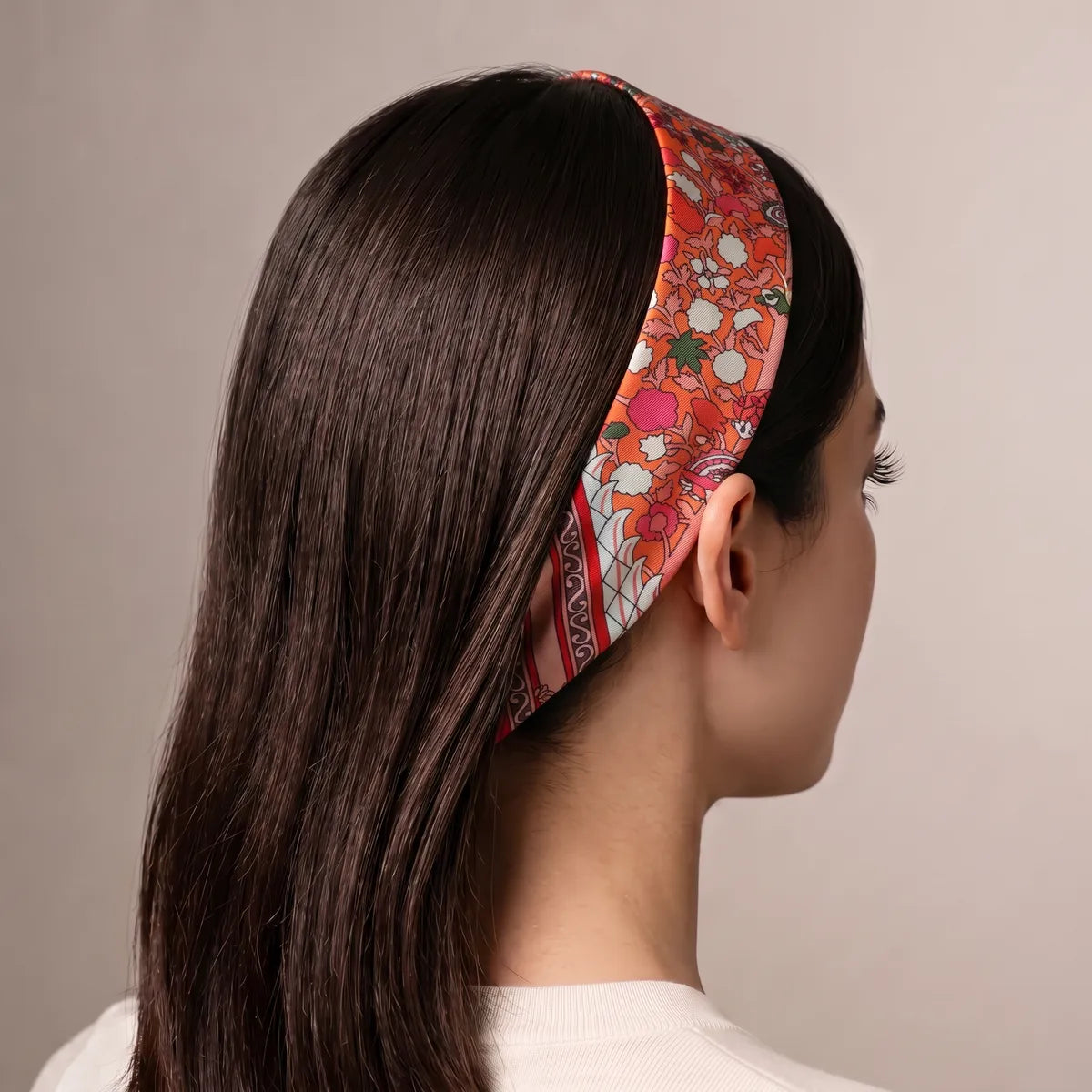 Coral skinny silk scarf used as a headband on long dark hair, seen from behind, blush stars along the band