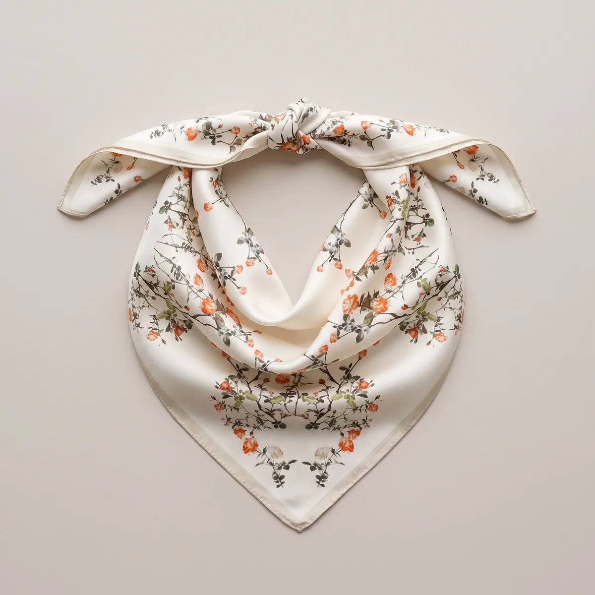 Coral blossom bandana with a knot at the top, laid flat so the flowering branches fall into a V