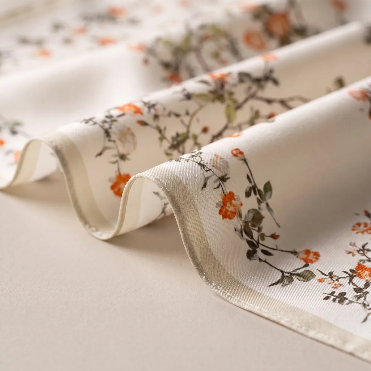 Loose waves of cream silk printed with coral blossoms, the cream border along the edge
