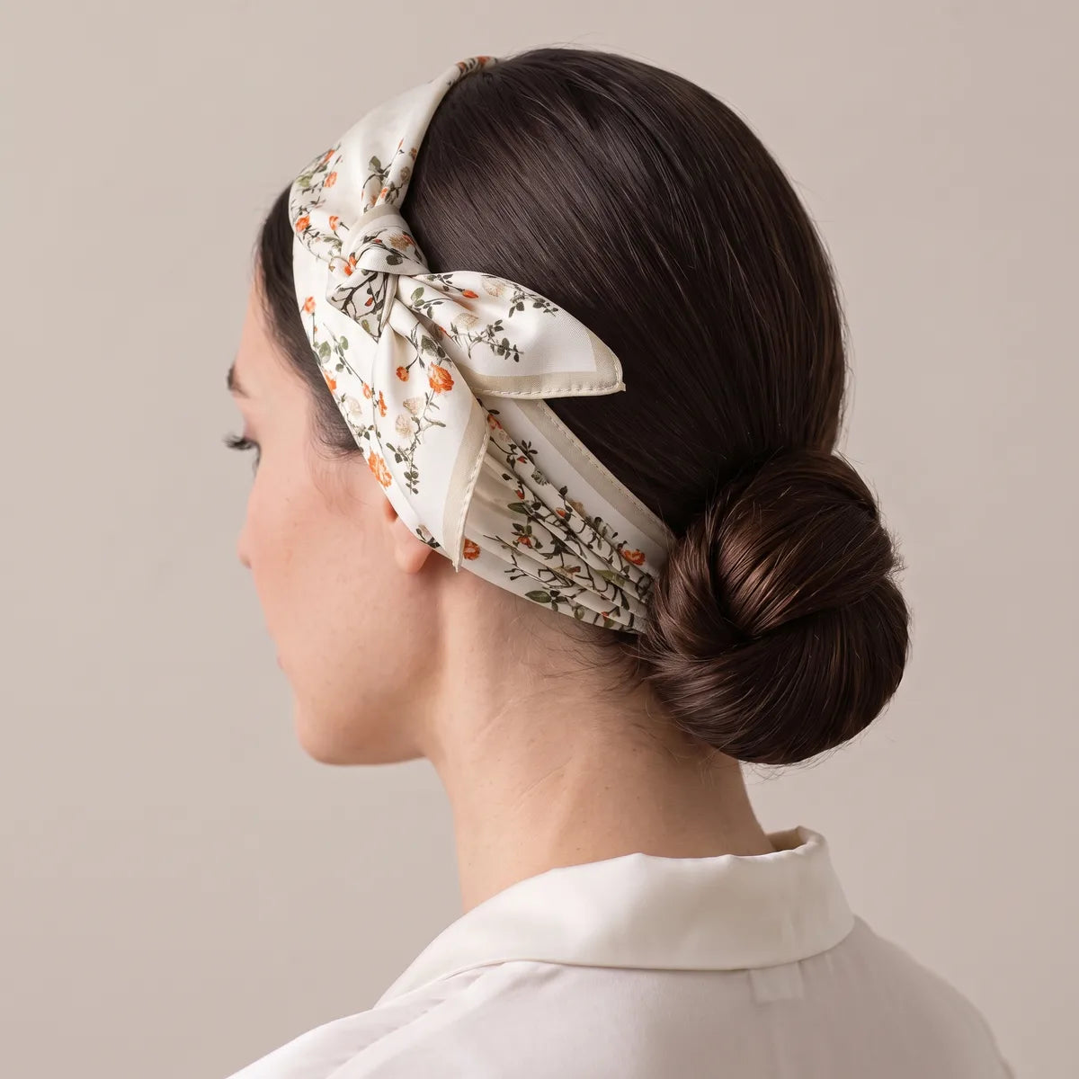 Botanical print silk scarf as a headband, knot above the ear, low bun at the back of the head