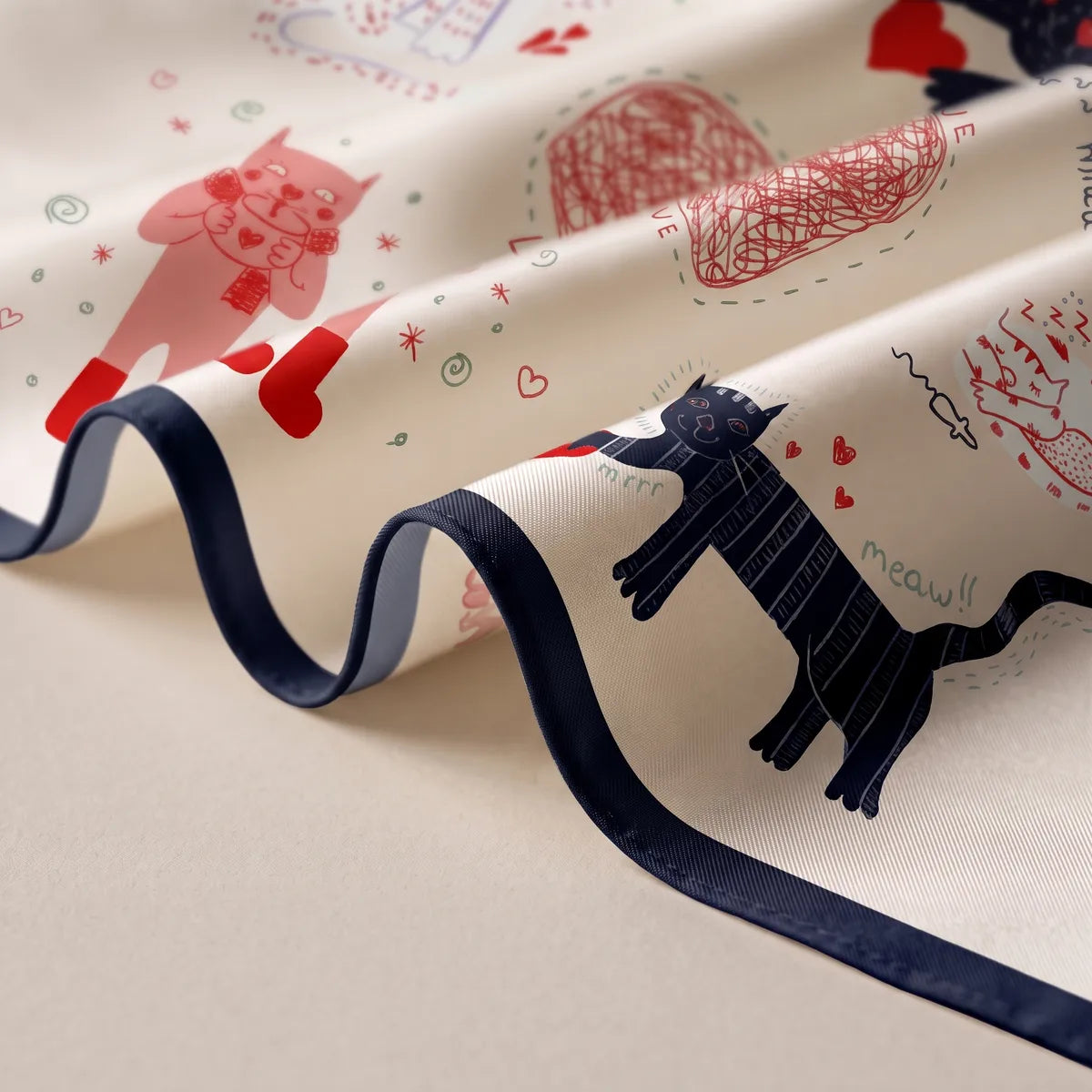 Draped cream bandana close up, a navy striped cat and red doodles above the navy hem