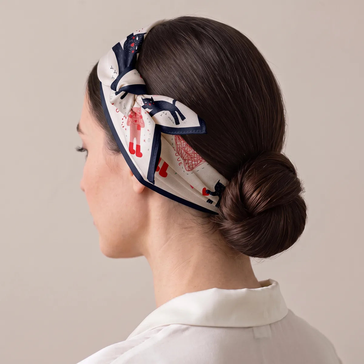 Cream bandana tied as a headband over a low bun, small cats along the band
