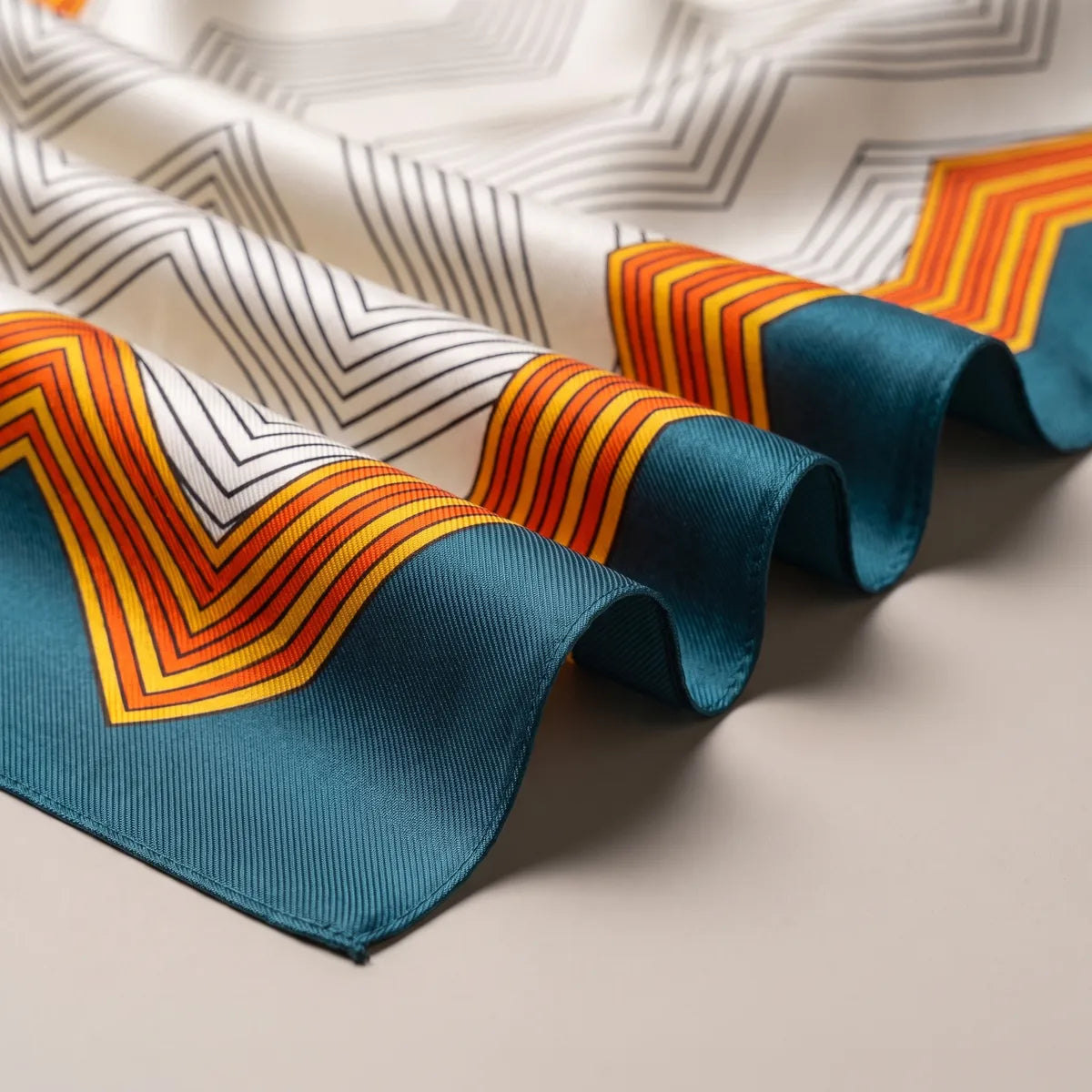 Folds of the chevron scarf: gray zigzag lines, orange and yellow stripes and the teal band