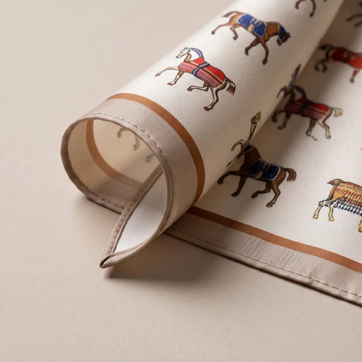 Curled-up corner of the horse scarf showing the camel band, a rust line and a faint reverse