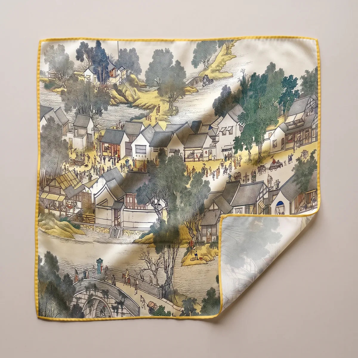 Cream landscape large square silk scarf laid flat: gray-roofed houses, crowds, trees and a stone bridge, mustard edge