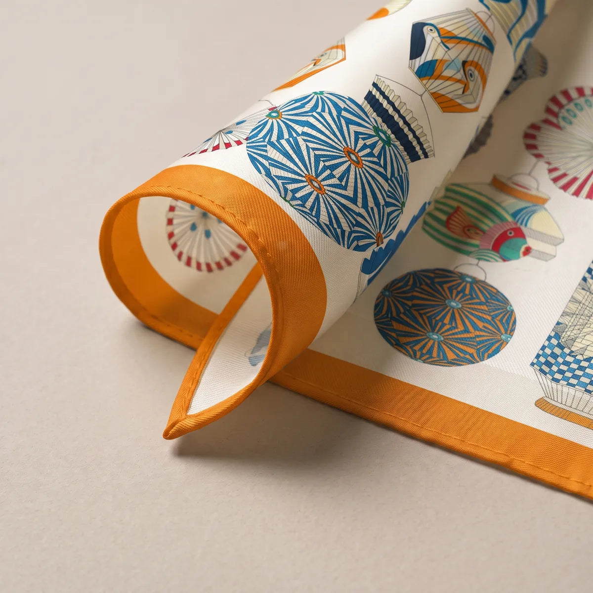 Lantern scarf corner rolled back: a blue patterned globe, the orange band and the pale reverse
