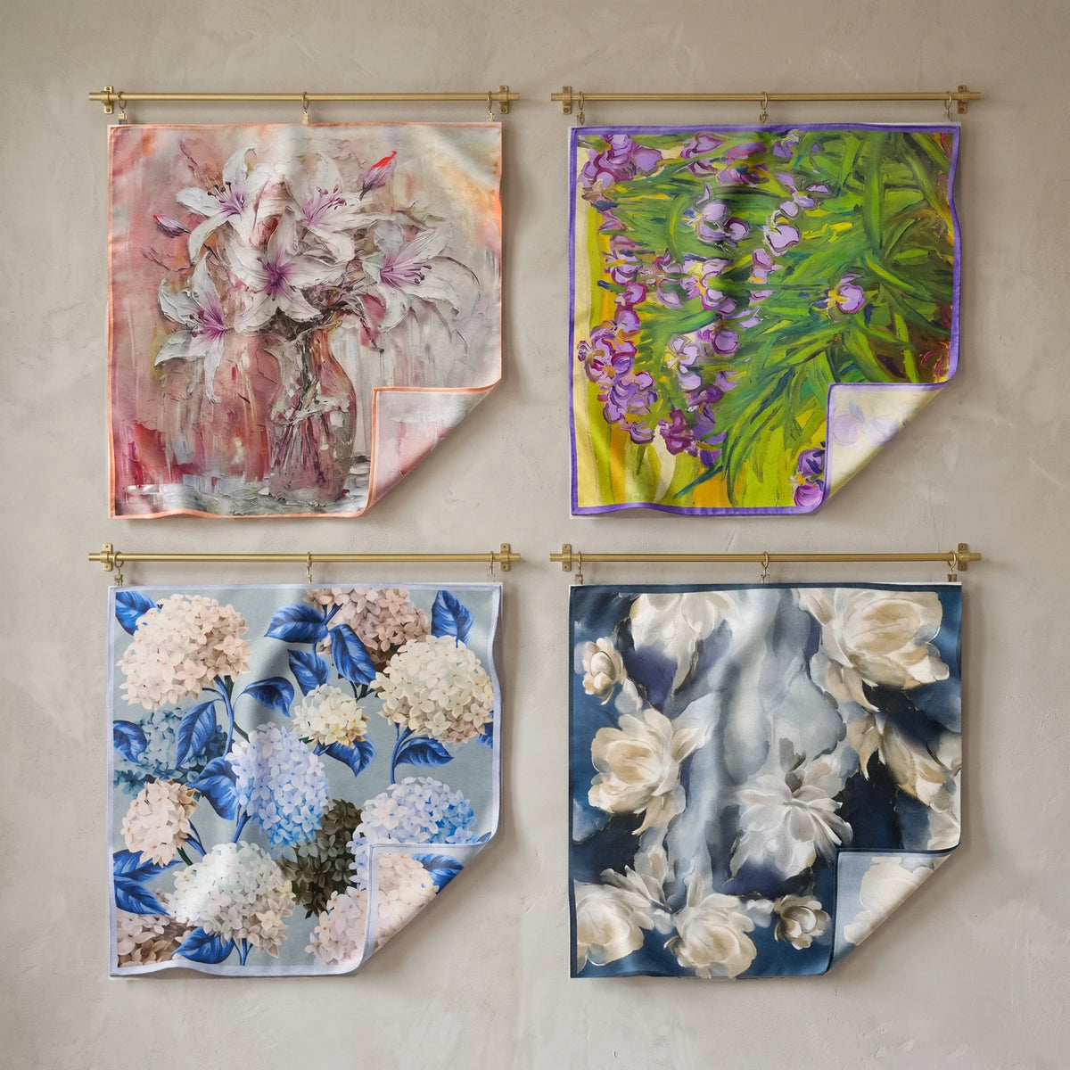 Four floral silk bandanas with lilies, irises, hydrangeas and navy blooms hung in a grid on brass rods