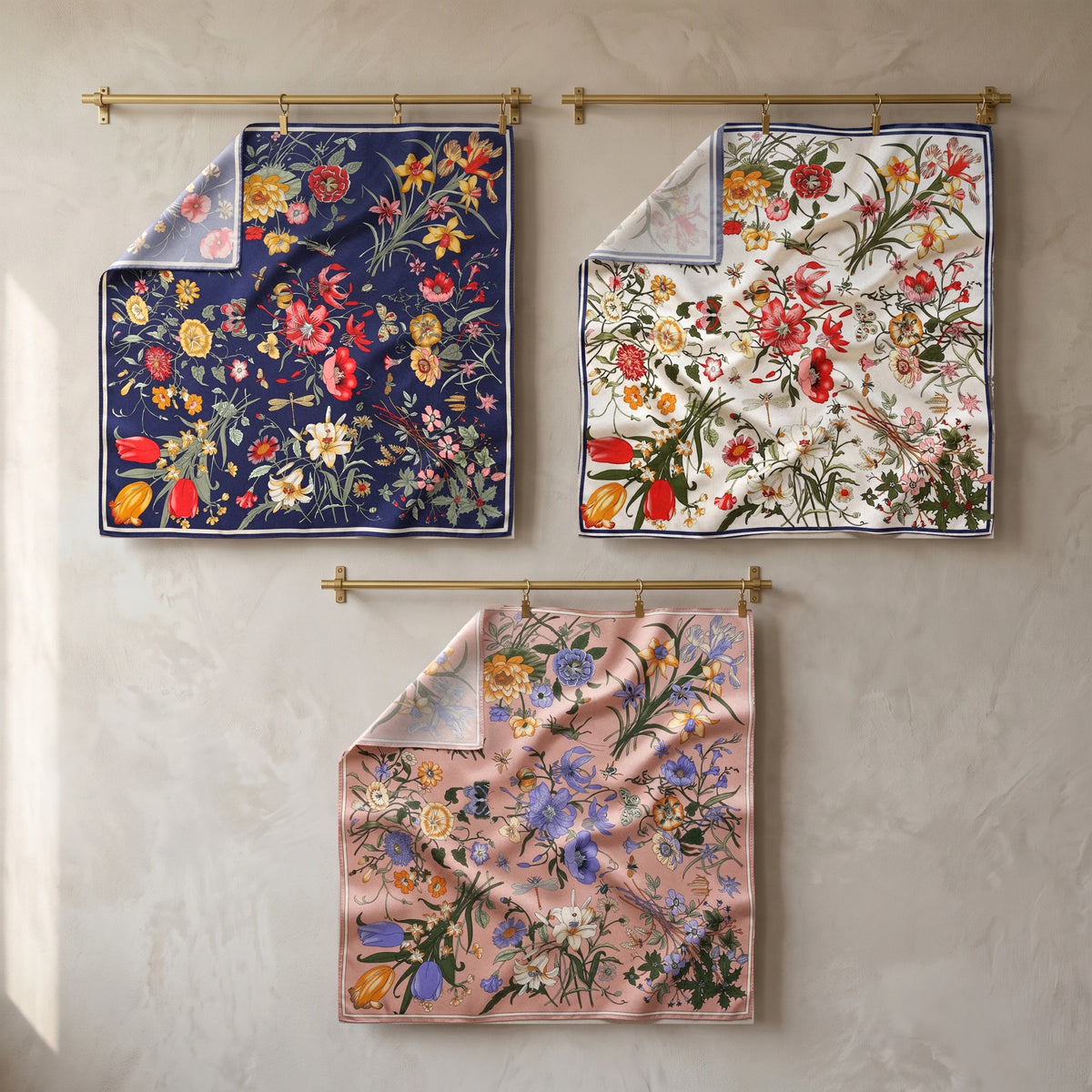 Navy, cream and pink floral silk shawls hanging flat from brass rods against a greige wall