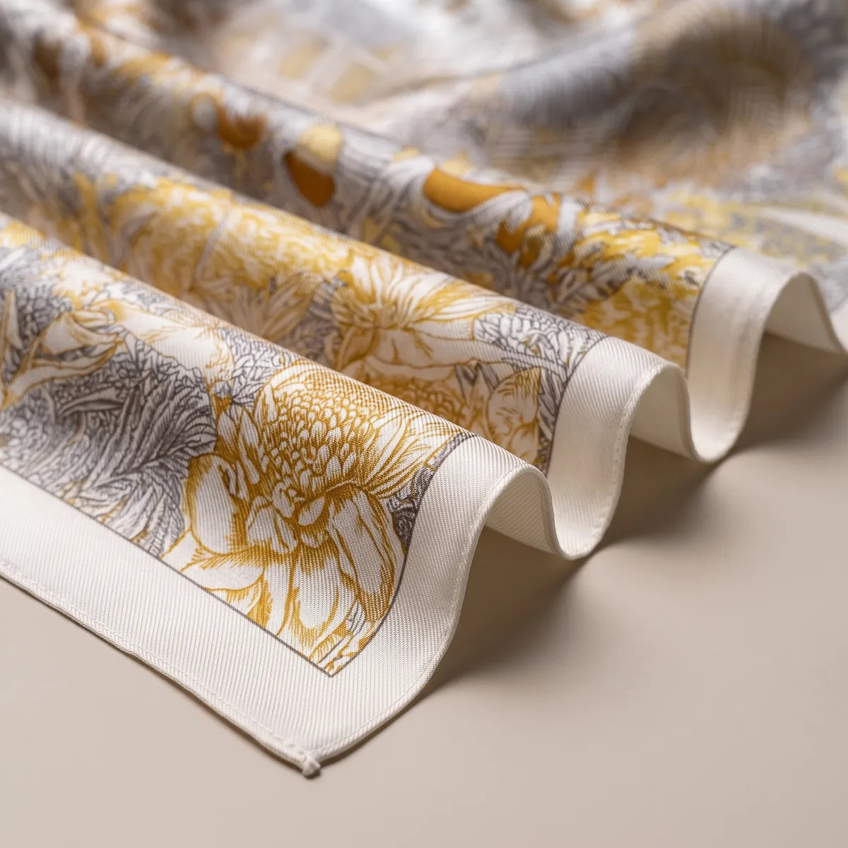 Folds of the tropical scarf showing a mustard bloom, gray fronds and the plain cream edge