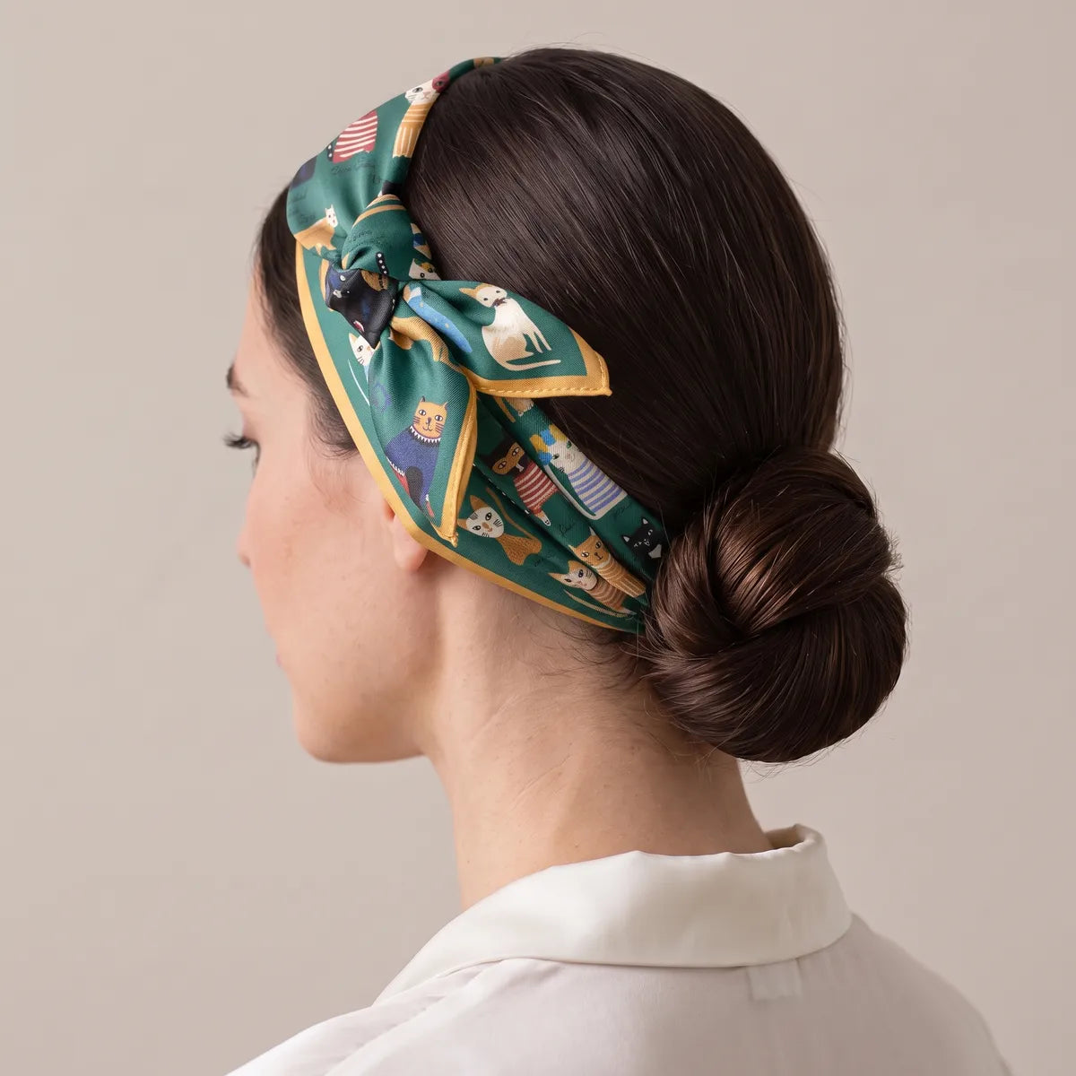 Cats marching along a green silk headband, the knot high above one ear and a low bun behind