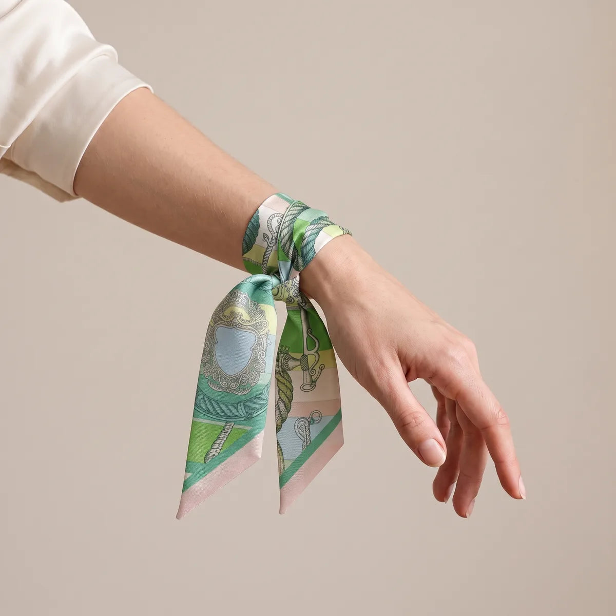 Green and pink skinny scarf knotted around the wrist, rope motif on the hanging end