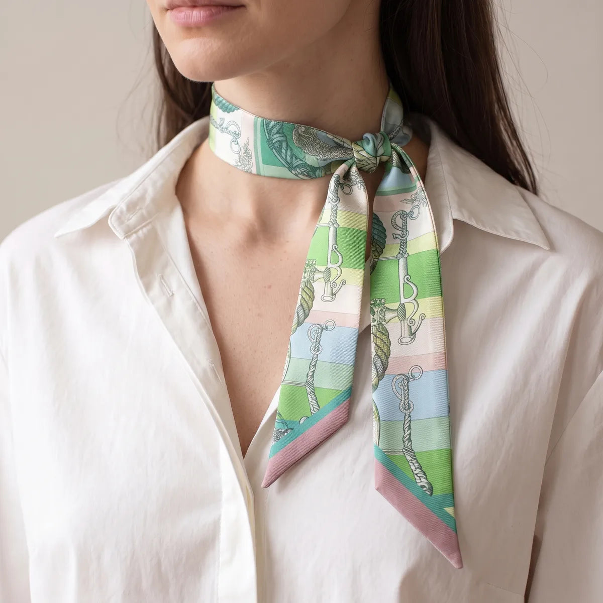 Green chain print skinny scarf with a side knot at the collar, worn over a white shirt