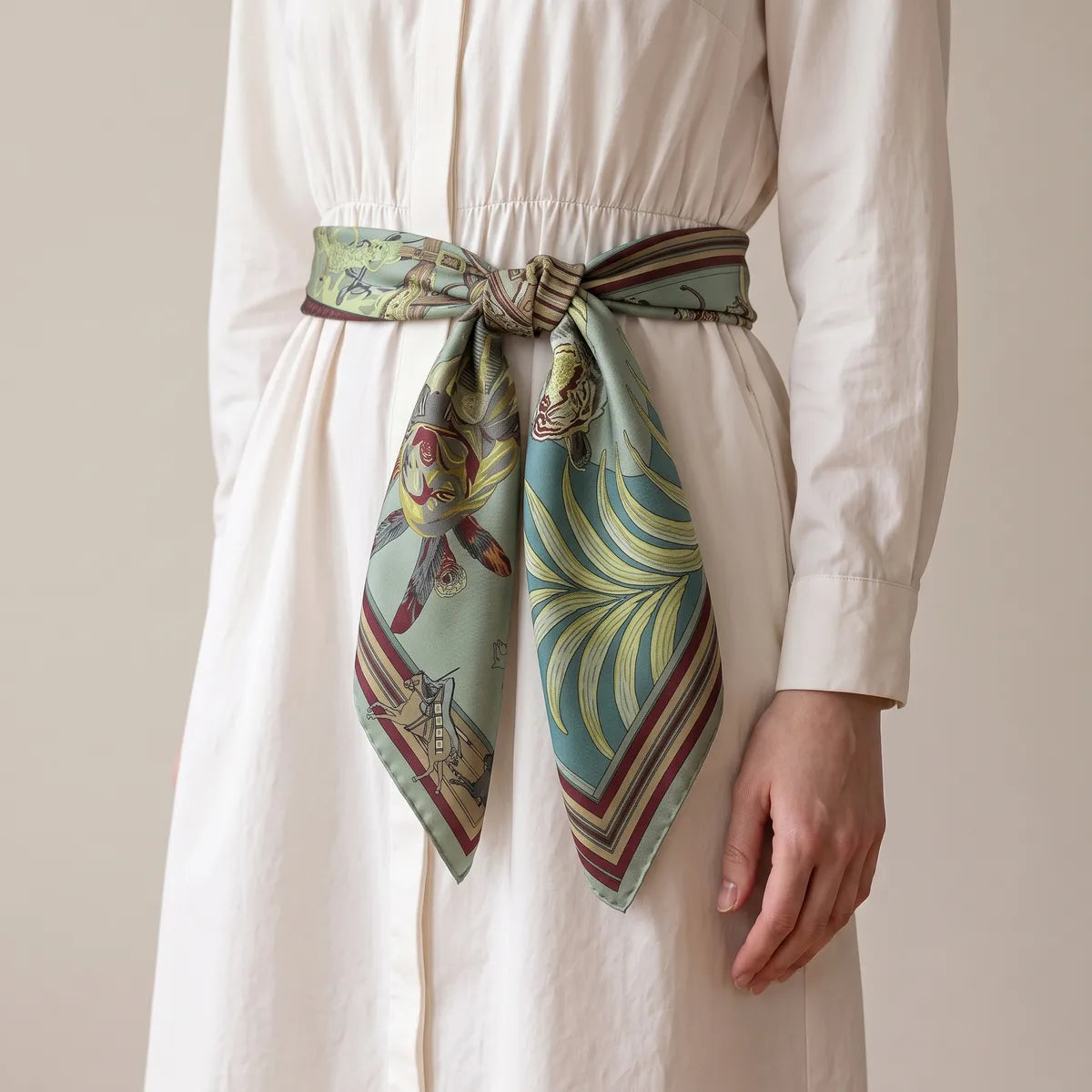 Horse print large square silk scarf knotted as a sash around the waist of a white shirtdress