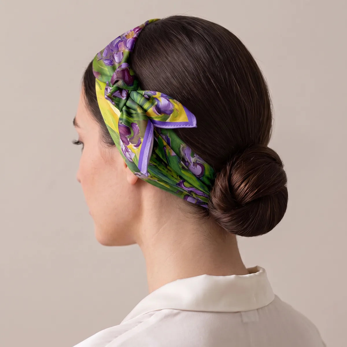 Iris silk bandana folded into a headband and knotted at the side just above the ear, dark hair in a low bun
