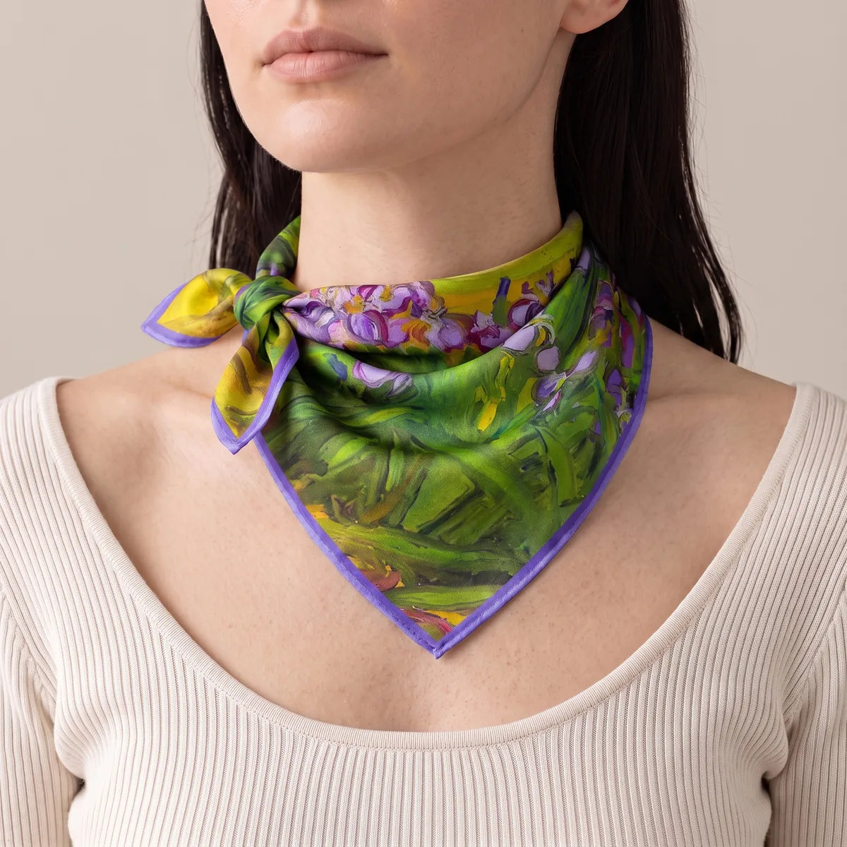 Woman in an ivory knit top wearing the green and purple iris bandana knotted at the side of her neck