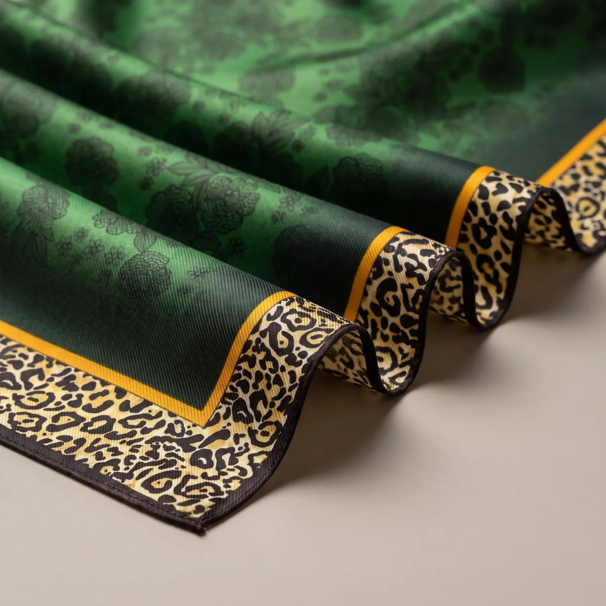 Folds of emerald silk with darker printed roses, edged by a mustard line and a sand and black leopard band