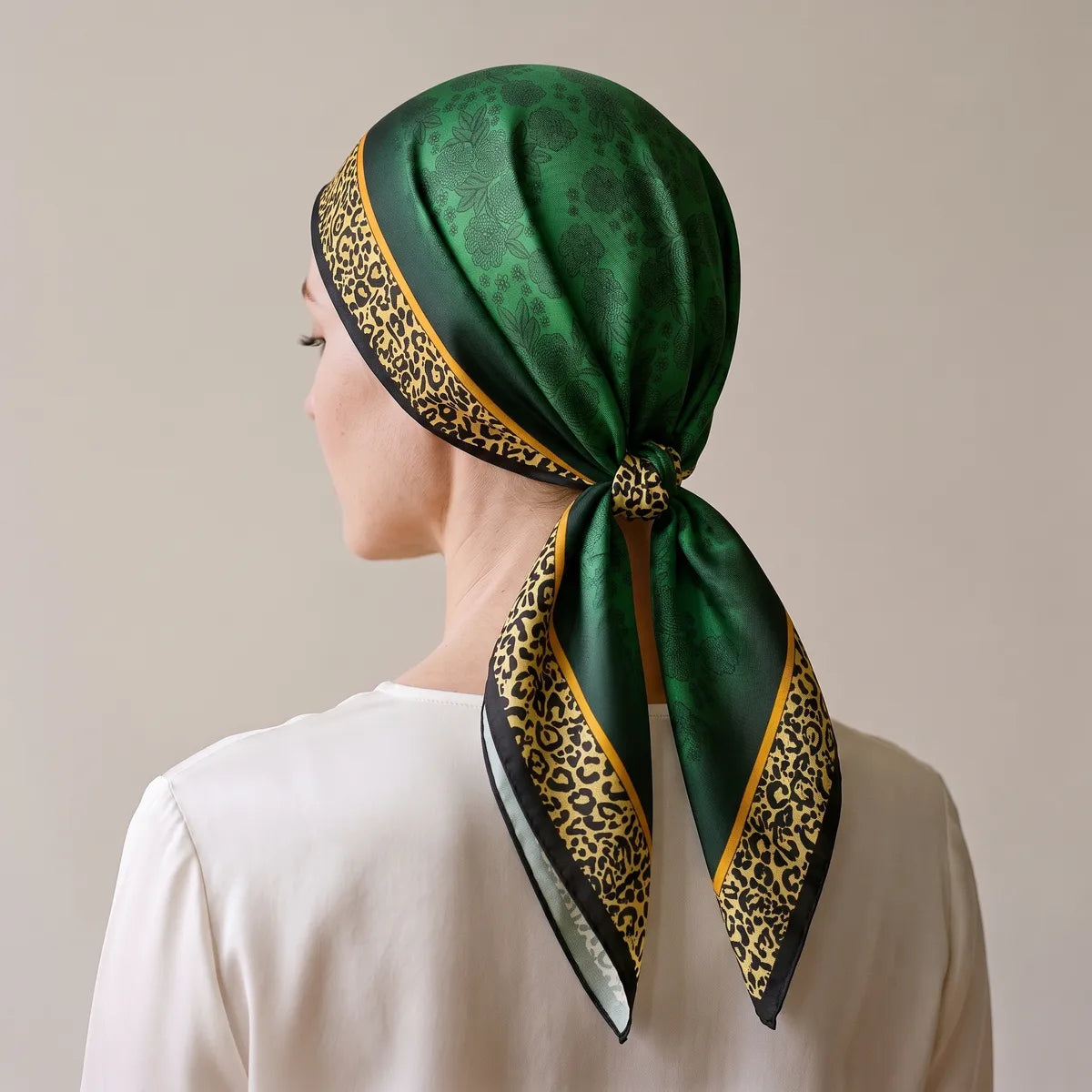 Green silk scarf covering the hair, leopard border around the face, knotted at the nape