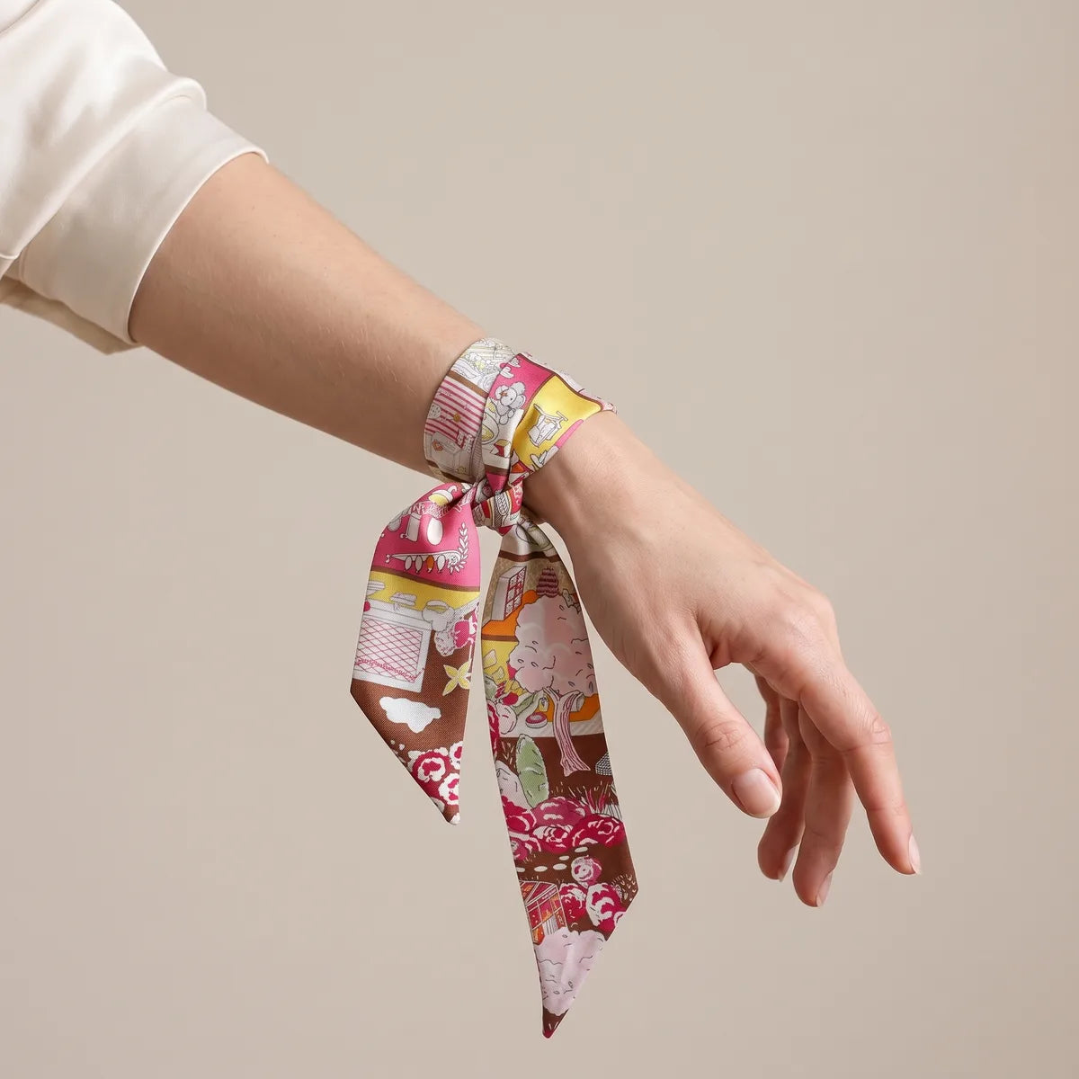 Pink house print skinny scarf tied around the wrist, a cloud motif on the brown tip